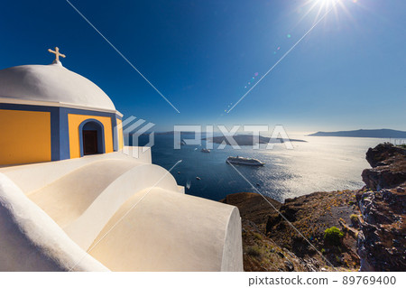 View over the bay of Santorini, Greece. Located at the cyclades archipelago in the Aegean Sea. Cruise ships dock in the bay bringing water to tourists on the small island. Small christian chapel 89769400