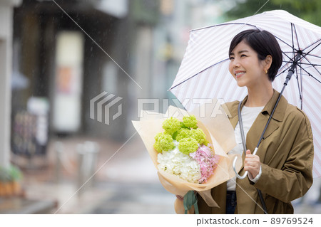A woman walking with a hydrangea on a rainy day 89769524