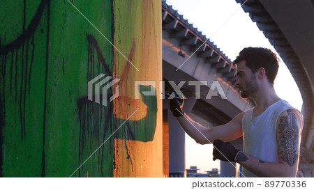 A man standing near the wall with graffiti - holding a marker 89770336