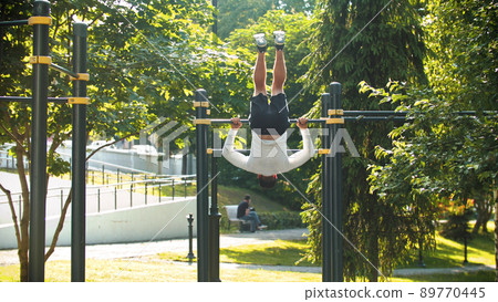 An athletic man exercising on the horizontal bar - rolls over 89770445
