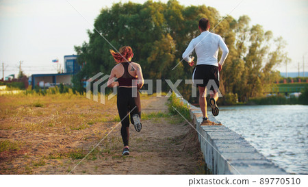 Man and woman running on the waterfront 89770510
