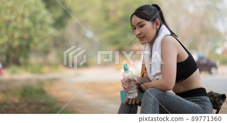 Young athletic woman holding water from a bottle after running in the park 89771360