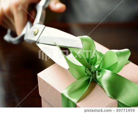 Decorating gift box with green ribbon using scissor Decorating gift box with green ribbon using scissor 89771959