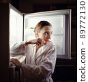 Young woman looking for some snack in fridge late at night 89772130