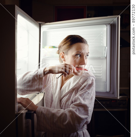 Young woman looking for some snack in fridge late at night 89772130