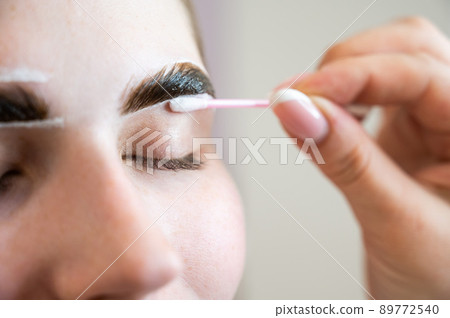 The master paints the eyebrows of a woman. The master paints the eyebrows of a woman. 89772540