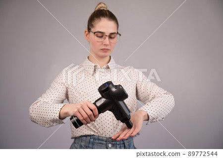 Caucasian business woman massaging her wrist with a percussion massager. 89772544