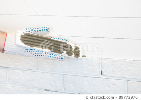 Professional Builder gluing decorative tile on wall. worker mounts decorative brick on wall Professional Builder gluing decorative tile on wall. worker mounts decorative brick on wall 89772976