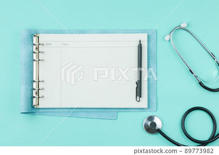 Stethoscope with notepad on green background. 89773982