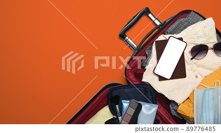 Smart phone, passport and clothes in suitcase. Preparing for the summer vacations 89776485
