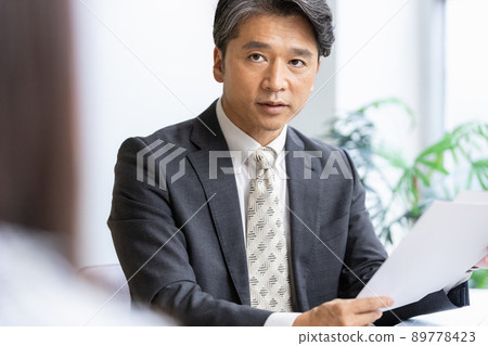 一位商人在查看文件時與前面的人交談 一位商人在查看文件時與前面的人交談 89778423