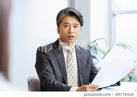 一位商人在查看文件時與前面的人交談 89778426