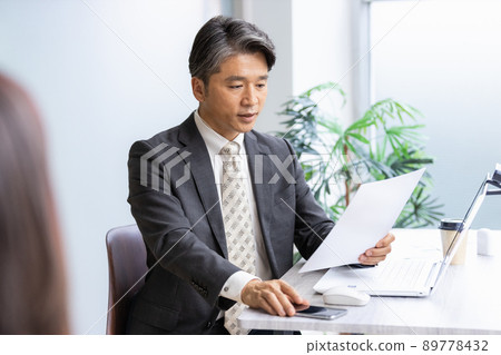 一位商人在查看文件時與前面的人交談 一位商人在查看文件時與前面的人交談 89778432