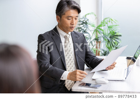 一位商人在查看文件時與前面的人交談 89778433