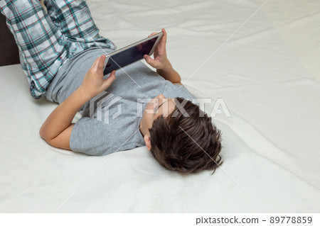 teenage boy lies on his back hold digital tablet teenage boy lies on his back hold digital tablet 89778859
