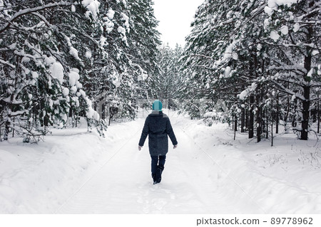 A lonely girl is walking in the winter snowy forest. Back view A lonely girl is walking in the winter snowy forest. Back view 89778962