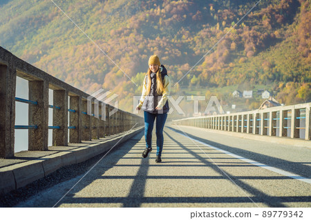 Montenegro. Woman touriste in background of Dzhurdzhevich Bridge Over The River Tara foggy morning. Travel around Montenegro concept. Sights of Montenegro Montenegro. Woman touriste in background of Dzhurdzhevich Bridge Over The River Tara foggy morning. Travel around Montenegro concept. Sights of Montenegro 89779342