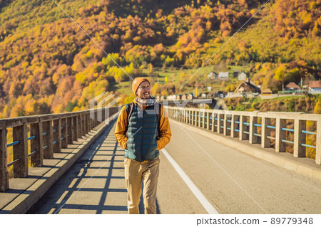 Montenegro. Man touriste in background of Dzhurdzhevich Bridge Over The River Tara foggy morning. Travel around Montenegro concept. Sights of Montenegro 89779348
