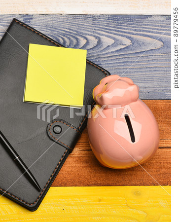 Moneybox with pig face near organizer and pen. Moneybox with pig face near organizer and pen. 89779456