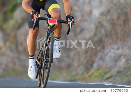 Male cyclist riding racing bicycle, man cycling on countryside summer road. Training for triathlon or cycling competition 89779960