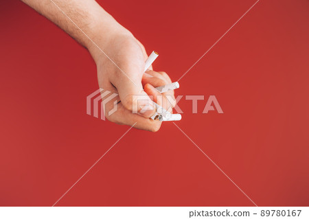 Hand crushes cigarettes against red background 89780167