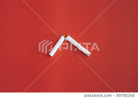 Broken cigarette in half on red background Broken cigarette in half on red background 89780168