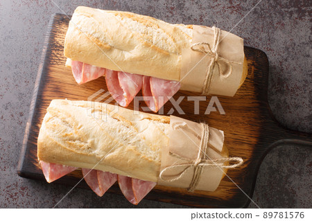 Jambon beurre is a simple and classic Parisian sandwich made with salted French butter and spiced ham closeup on the wooden board. Horizontal top view 89781576
