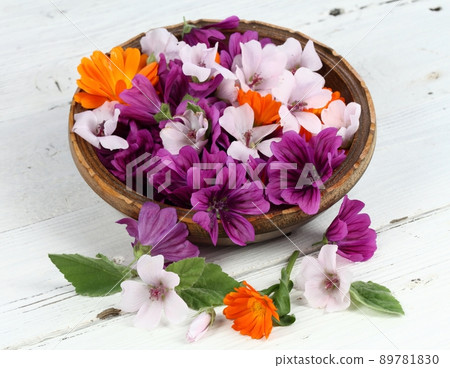 Beautiful flowers of medicinal herbs  in a bowl on the white wooden table 89781830