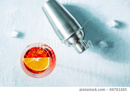 Aperol cocktail with a fresh orange slice, a shaker, and ice cubes Aperol cocktail with a fresh orange slice, a shaker, and ice cubes 89781885
