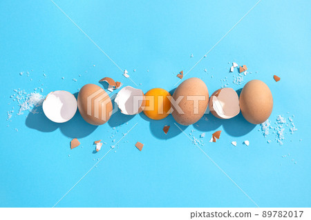 Brown chicken eggs, eggshell and egg yolk on blue background. Flat lay composition. Brown chicken eggs, eggshell and egg yolk on blue background. Flat lay composition. 89782017