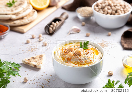 Classic hummus in a bowl with ingredients on light background. 89782113