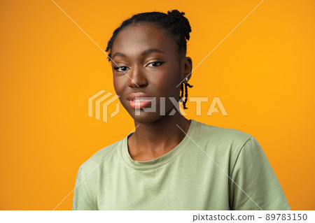 Studio shot of black girl looking suspiciously with skeptical expression in yellow studio Studio shot of black girl looking suspiciously with skeptical expression in yellow studio 89783150