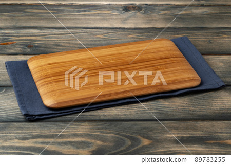 Wooden board with kitchen napkin on dark wooden table 89783255