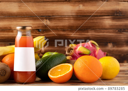 Fruit drink in glass bottle and frsh fruits on wooden background Fruit drink in glass bottle and frsh fruits on wooden background 89783285