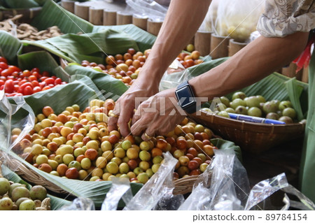 Hand selecting Monkey Apples in a basket. 89784154