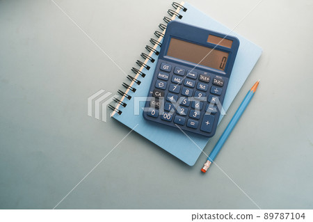 top view of blue calculator and notepad on color background  89787104