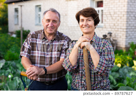 mature farmers posing with a harvest of vegetables in the garden mature farmers posing with a harvest of vegetables in the garden 89787627