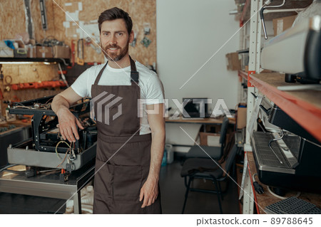 Portrait of repairman in uniform standing on workshop of coffee machines warehouse Portrait of repairman in uniform standing on workshop of coffee machines warehouse 89788645