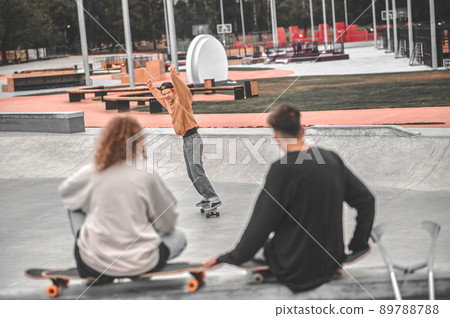 Guy sliding on skateboard and friends with back 89788788