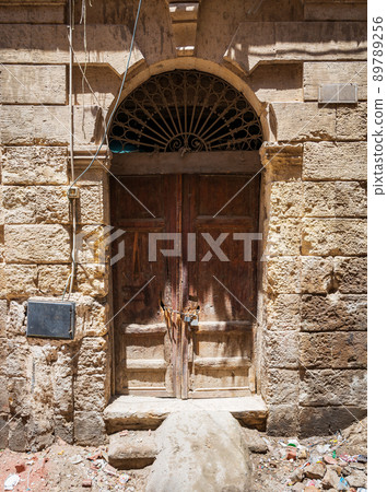 Broken wooden door on grunge stone bricks wall in abandoned district 89789256
