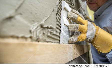 Closeup of workman carefully positioning an ornamental tile in a glue 89789876