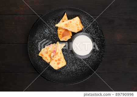 Top view of thin pancakes stuffed with ham and cheese 89790996