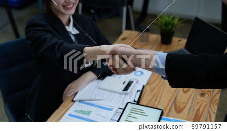 Two business people shake hands after accepting a business proposal together, a handshake is a universal homage, often used in greeting or congratulations. Two business people shake hands after accepting a business proposal together, a handshake is a universal homage, often used in greeting or congratulations. 89791157