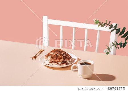 Cake on plate with golden fork and cup of coffee on the table against pink background Cake on plate with golden fork and cup of coffee on the table against pink background 89791755