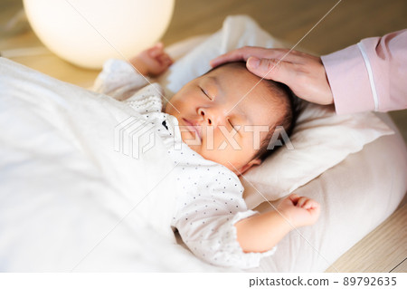 晚上睡覺，媽媽撫摸著她的頭，還有一個熟睡的嬰兒 89792635