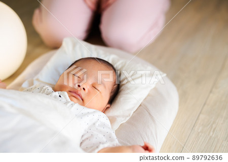 晚上睡覺,一個熟睡的嬰兒的腳和一個看著的媽媽 晚上睡覺,一個熟睡的嬰兒的腳和一個看著的媽媽 89792636