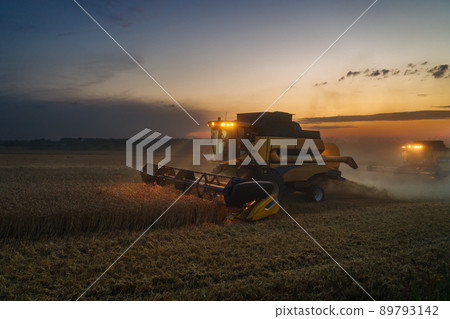 Combine harvester harvests ripe wheat. Ripe ears of gold field on the sunset cloudy orange sky background. . Concept of a rich harvest. Agriculture image 89793142