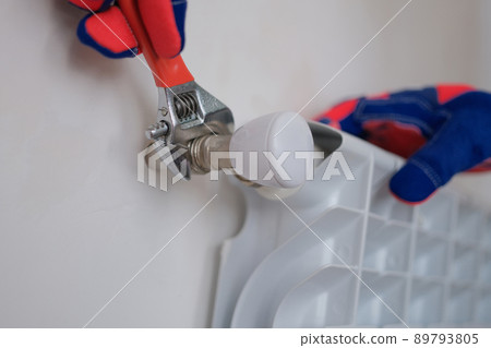 Plumber installing heating radiator in apartment or house 89793805