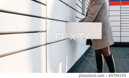 Delivery locker. Post automat terminal and hands with parcel courier box. Online purchase delivery service concept. 89794154