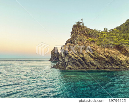 green mountains with plants above in the sea. a rock in the water, a tiny island for sailors. tourist resort. travel in hot countries 89794325